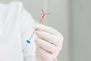 Holding an IUD birth control copper coil device in hand, used for contraception - front view